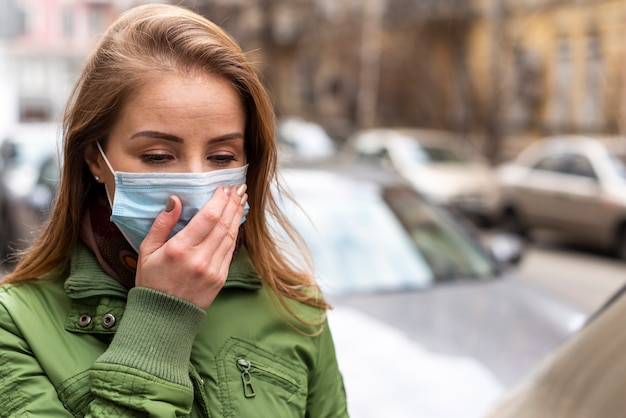 Woman wearing a mask and holding her hand on her face