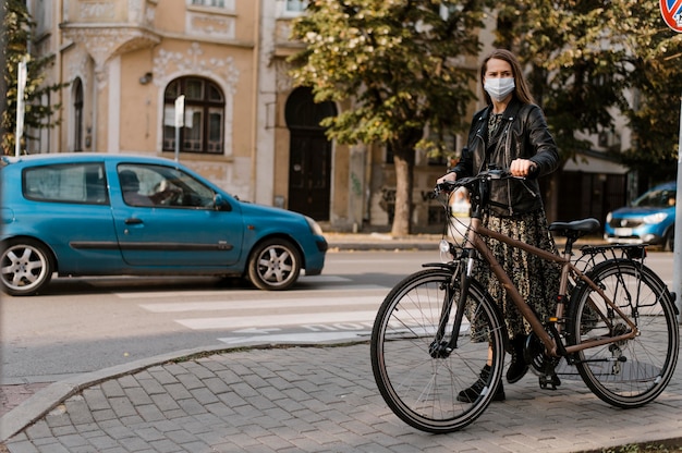 Woman wearing medical mask and bicycle long view