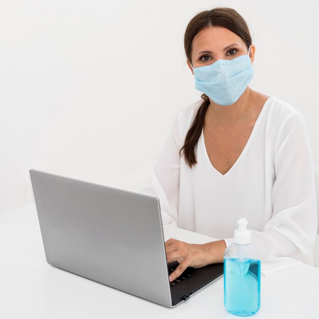 Женщина в медицинской маске рядом с дезинфицирующим средством для рук