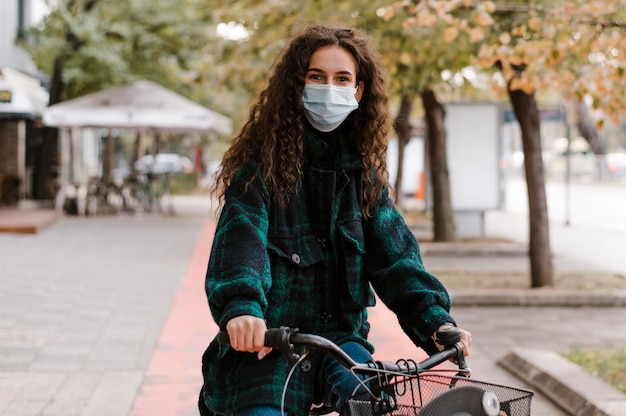 Woman wearing medical mask and riding the bicycle front view