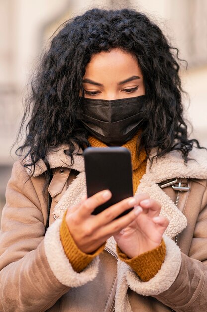 Woman wearing a medical mask while checking her phone