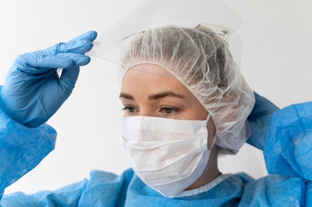 수술 마스크와 의료 보호 장비를 착용하는 여자