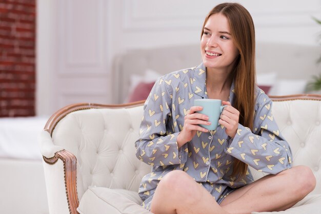 Женщина носит пижаму и пьет чай
