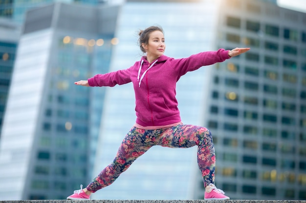 Woman wearing pink in Warrior 2 pose