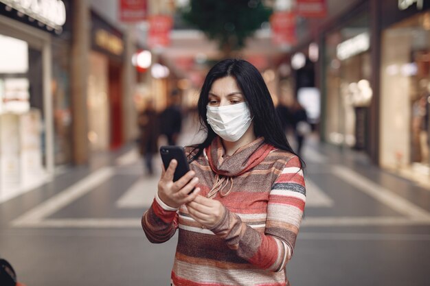 휴대 전화를 사용하여 보호 마스크를 착용하는 여자