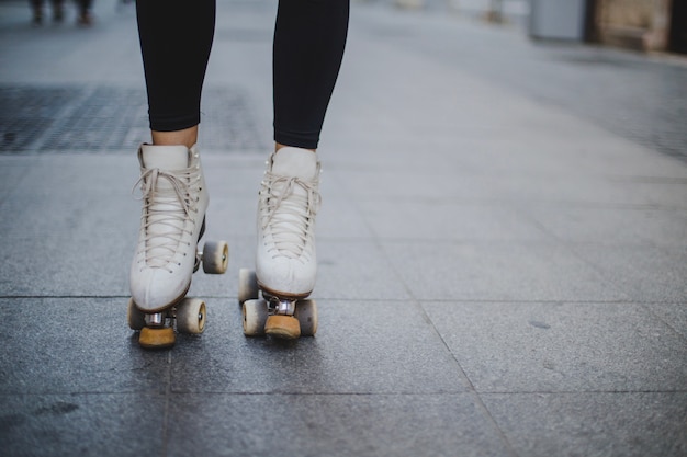 Женщина, носить rollerskates, стоя на тротуаре