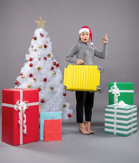 クリスマスツリーの横に荷物とサンタクロースの帽子をかぶっている女性