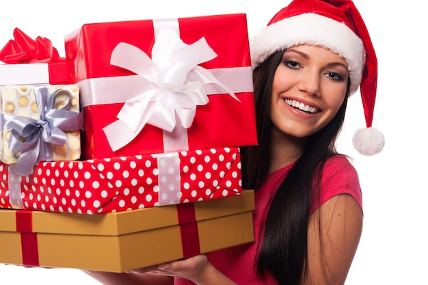 Женщина в шляпе санта-клауса держит стопку рождественских подарков