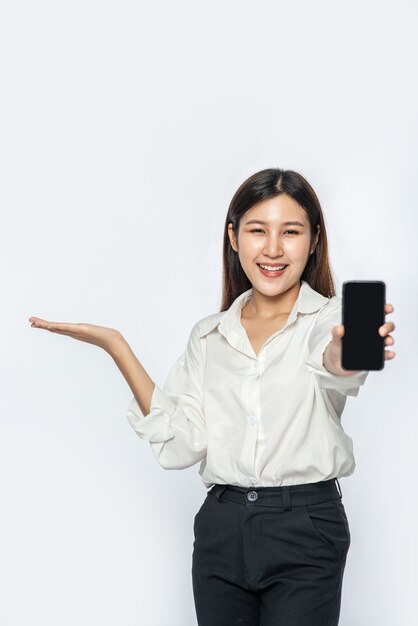 A woman wearing a shirt and holding a smartphone