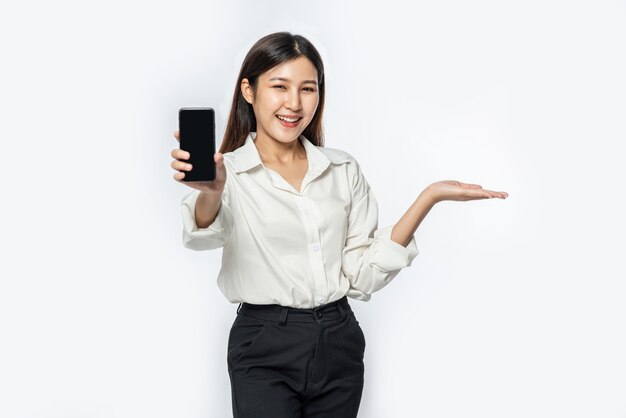 A woman wearing a shirt and holding a smartphone