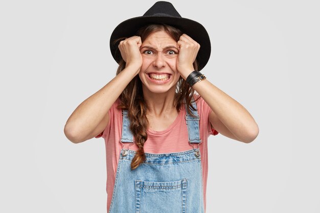 Woman wearing stylish hat and overalls