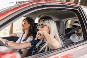 Foto gratuita donna che indossa occhiali da sole alla guida di auto con i suoi amici