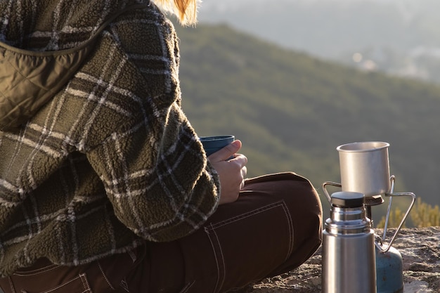 Woman wearing sweatshirt drinking tea on top of mountain