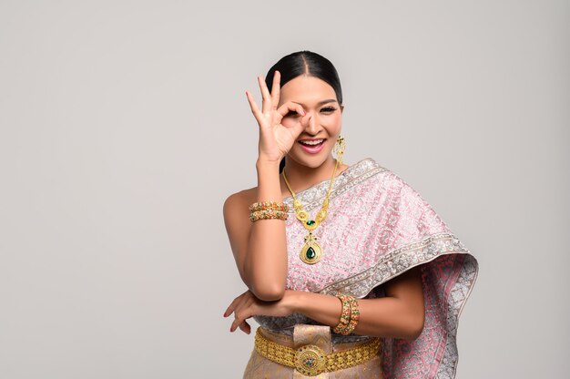 woman wearing Thai clothes and hand symbolizing OK