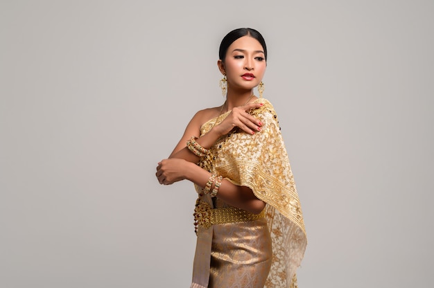 Free photo woman wearing thai clothes and right hand grasping her shoulders.