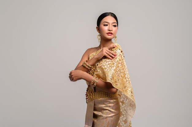 woman wearing Thai clothes and right hand grasping her shoulders.