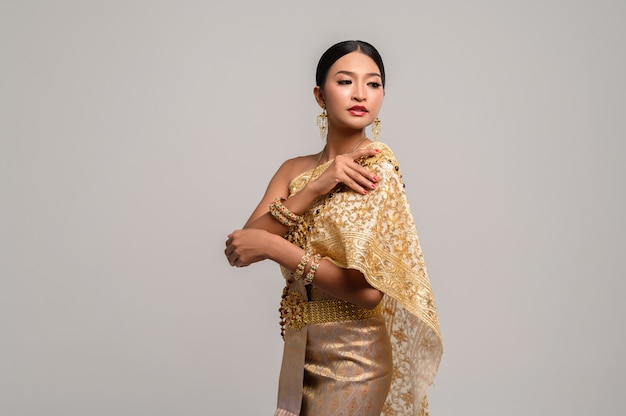 woman wearing Thai clothes and right hand grasping her shoulders.