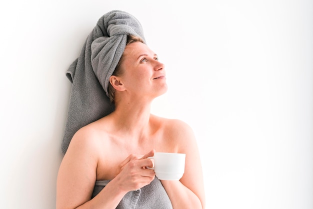 Woman wearing towels holding a white cup