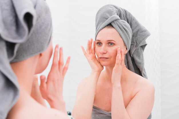 Woman wearing towels and looking in the mirror