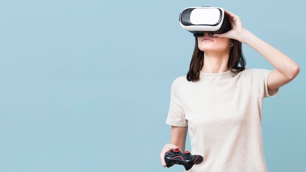 Free photo woman wearing virtual reality headset and holding remote control