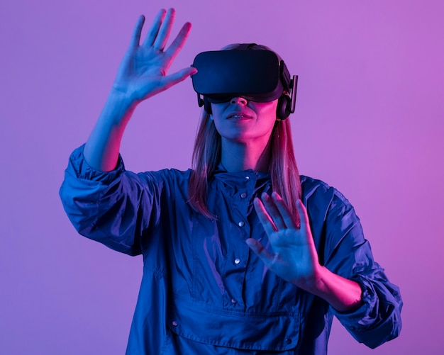 Free photo woman wearing vr glasses with purple light