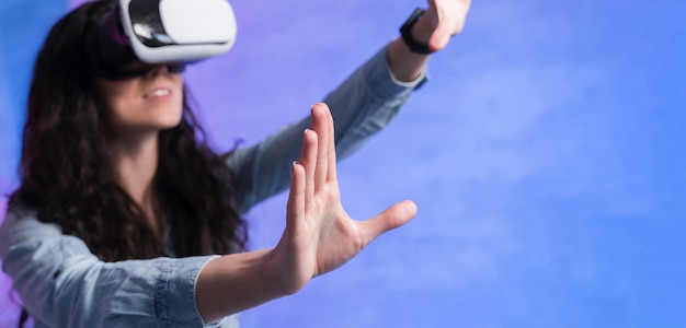 Free photo woman wearing a vr set and holding hands in the air