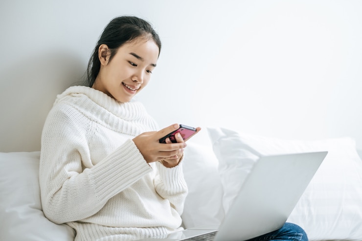 無料Photo スマートフォンで遊ぶ白いシャツを着た女性