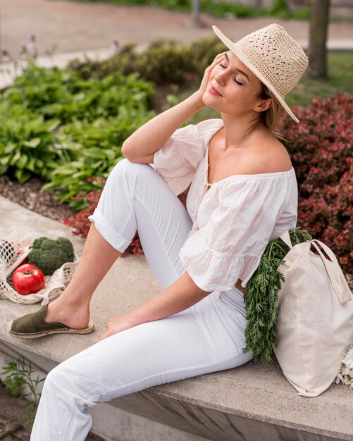 Woman wearing white sitting next to veggies