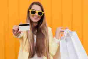 Free photo woman wearing yellow clothes holding shopping card