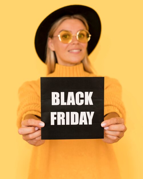 woman wearing yellow shirt holding black friday squared card
