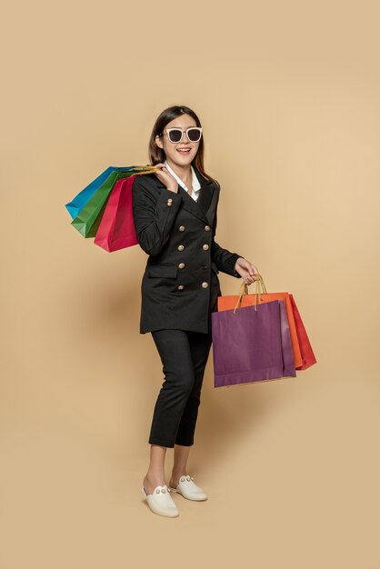 The woman wears dark clothes and glasses, along with many bags, to go shopping