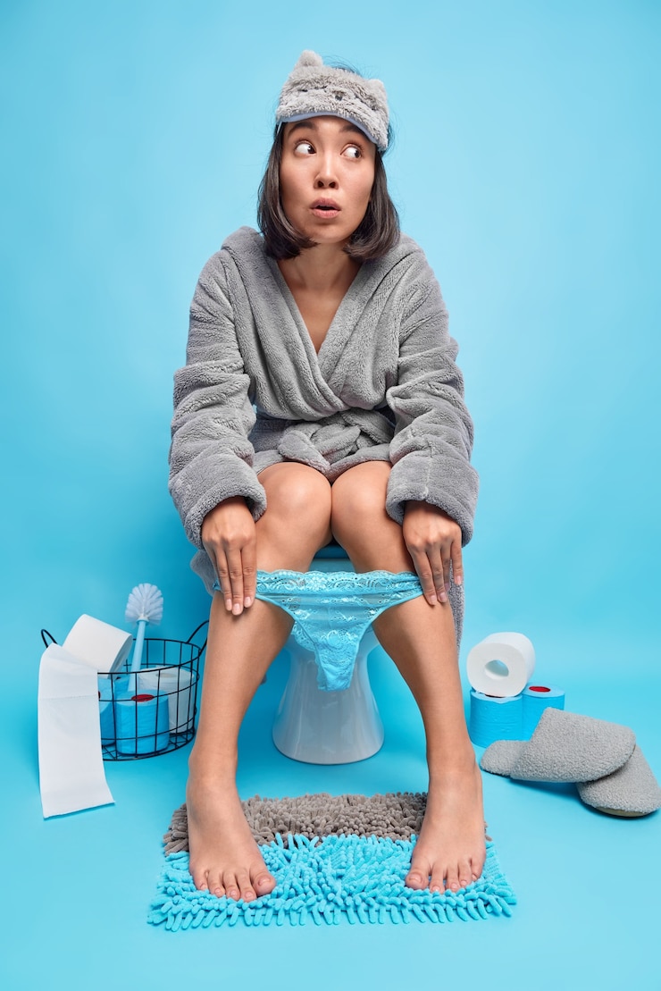 무료 Photo 여자는 잠옷 목욕 가운과 변기에 오줌 누는 다리에 레이스 팬티를 입고 화장실 방에서 포즈