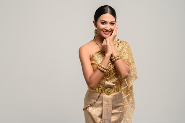 The woman wears Thai dress and hands touch the face.