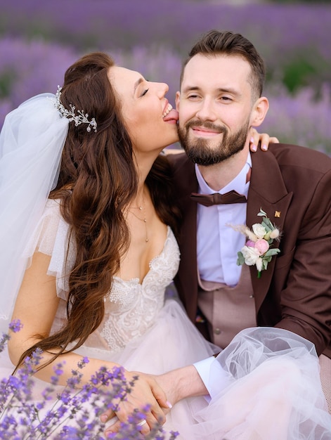Woman in wedding dress touching cheek of man while posing in field