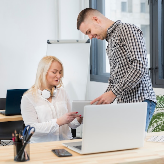 Woman in wheelchair and colleague conversing over tablet