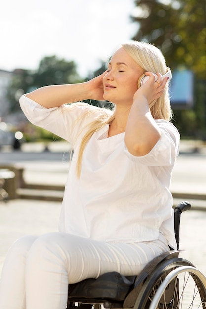 Woman in wheelchair enjoying music on headphones outside