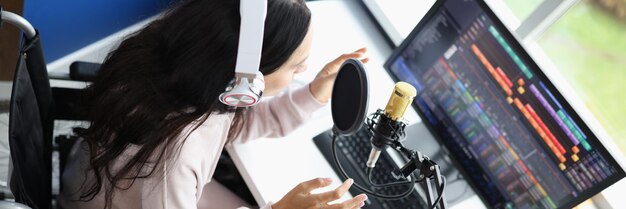 Woman in wheelchair in headphones with microphone is conducting online live broadcast working