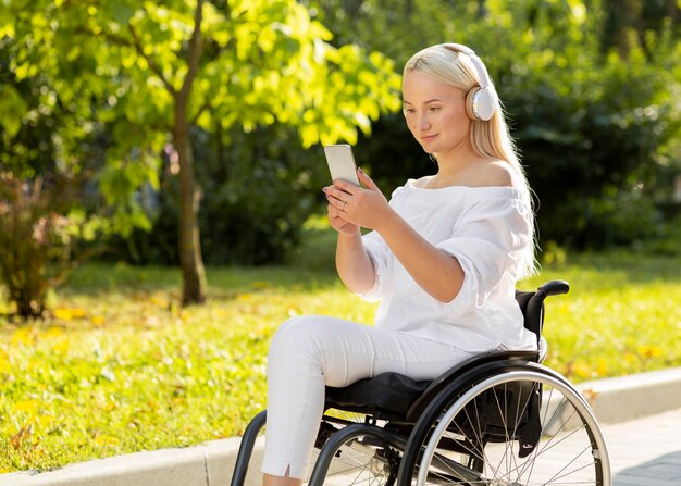 핸드폰으로 야외에서 음악을 듣고 휠체어에 여자