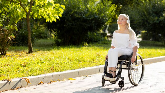 Woman in wheelchair listening to music outdoors