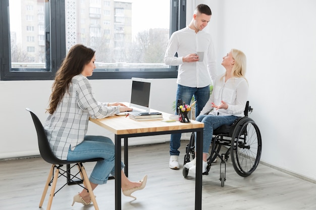 Foto gratuita donna in sedia a rotelle presso l'ufficio con i colleghi