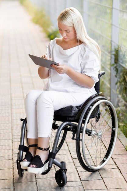 Woman in wheelchair outdoors with tablet