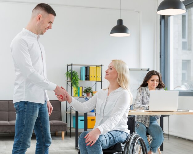 Woman in wheelchair shaking hand with coworker