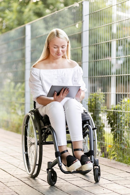 Foto gratuita donna in sedia a rotelle facendo uso della compressa