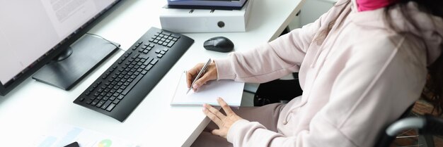 Woman in wheelchair works at computer in workplace remote work for people with disabilities