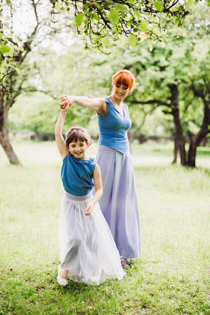 Woman whirls her little daughter posing in the park