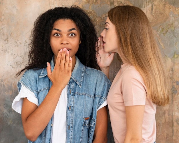 Woman whispering her friend a secret