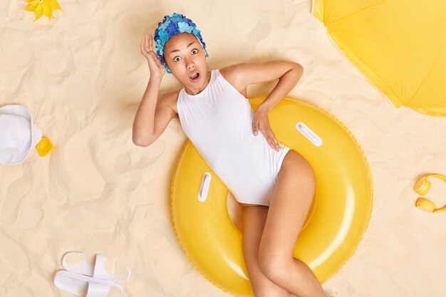 женщина в белом бикини имеет идеальную фигуру стройные ноги лежит на желтом накачанном плавает реагирует на шокирующие новости проводит свободное время на пляже в поездках за границу