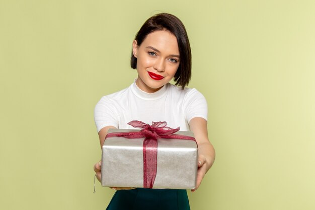 woman in white blouse and green skirt holding present box 
