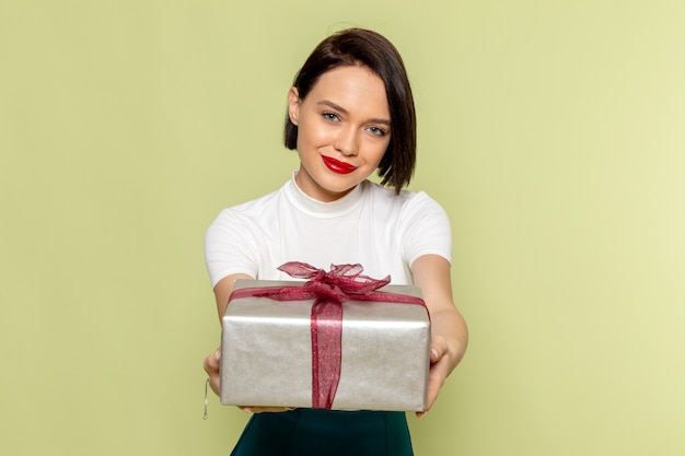 woman in white blouse and green skirt holding present box 