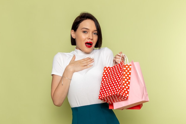 Free photo woman in white blouse and green skirt holding shopping packages